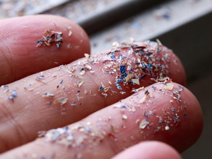 Foto close-up dari samping mikroplastik yang menempel di tangan manusia. Foto: Getty Images/iStockphoto/pcess609
