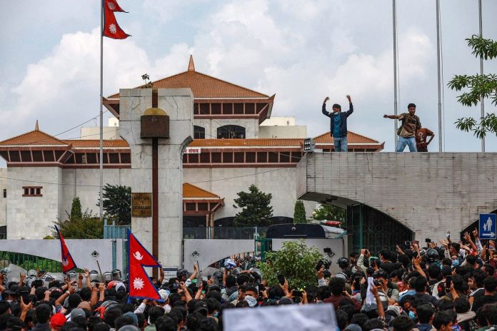 Para peserta demo Nepal berorasi di depan Gedung Parlemen di Kathmandu, Senin (8/9/2025). Demo ini menewaskan sedikitnya 19 orang. Kasus korupsi hingga larangan media sosial jadi landasan massa turun ke jalan.(AFP/PRABIN RANABHAT)